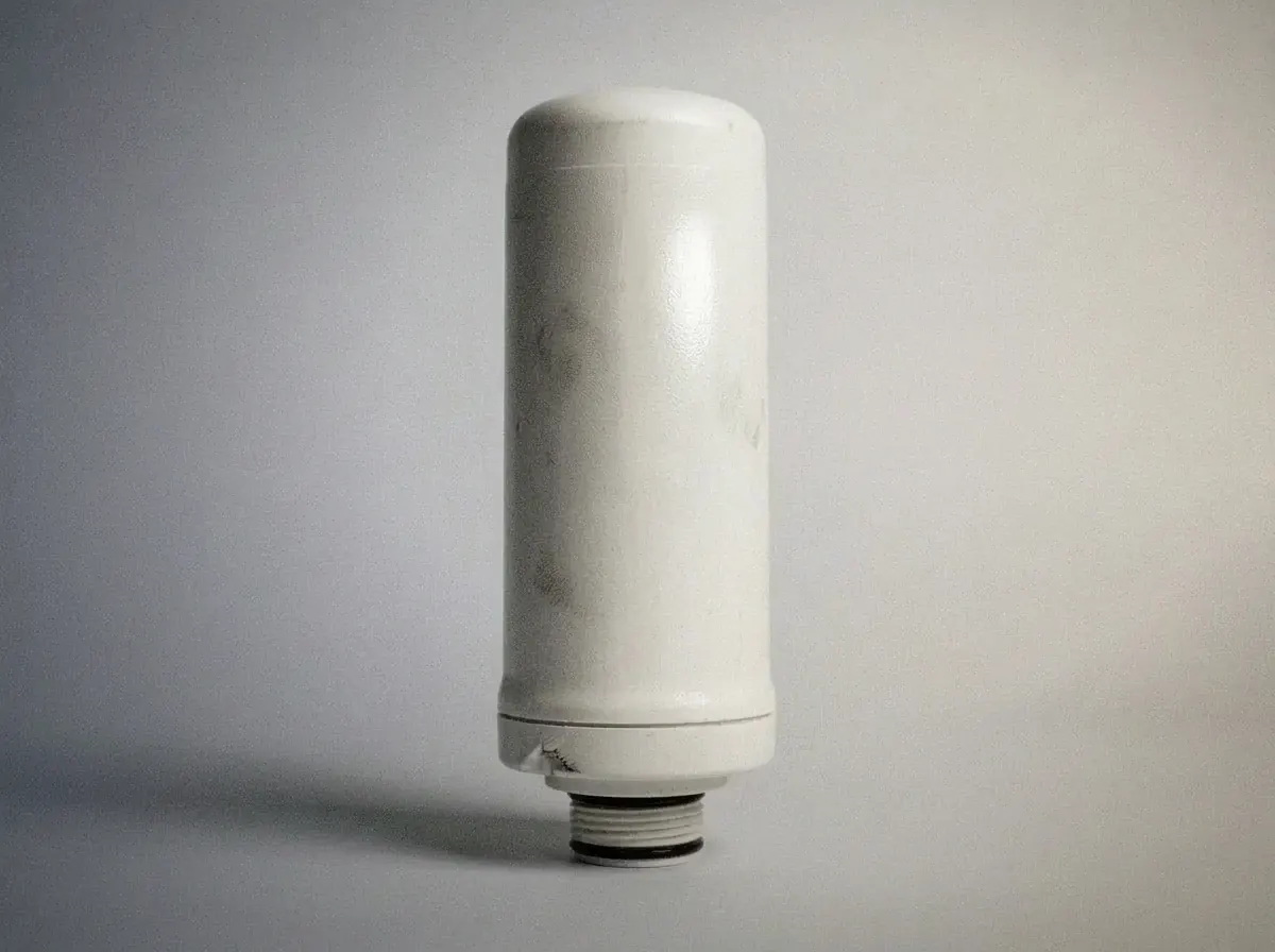 White cylindrical under-sink water filter cartridge with threaded connector, representing a whole-house or under-sink replacement filter
